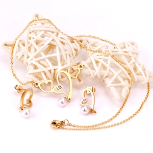Golden heart jewelry set with white pearls and small zircons on white background
