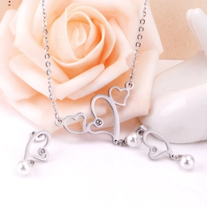 Macro detail of heart-shaped silver necklace and earrings set with pearls and rhinestones