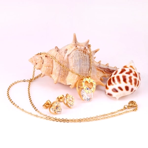 Elegant gold double heart jewelry set with necklace and earrings on a white beach background