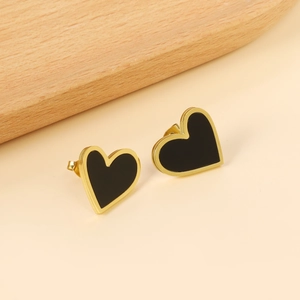 Boucles d'oreilles cœur dorées modernes avec émail noir sur fond beige minimaliste