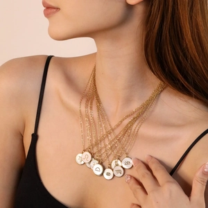 Détail de colliers superposés en or avec pendentifs zodiacaux blancs sur un mannequin