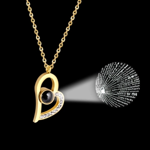 Macro shot of gold heart necklace showing circular multi-language I Love You projection