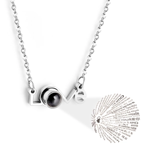Macro shot of silver LOVE necklace featuring a black projection stone with multi-language text
