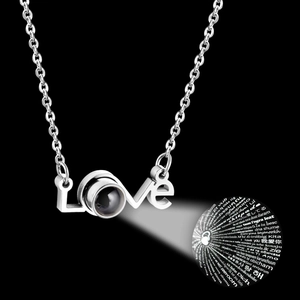 Detail of silver Love necklace showing 100 languages I love you projection on dark background