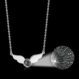 Macro shot of silver projection necklace with wings and I Love You stone on black background