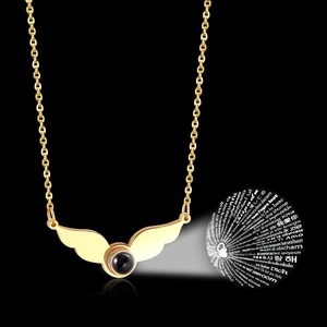 Detail view of gold wing heart necklace with 100 languages I Love You projection stone