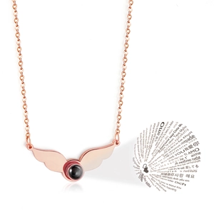 Detail of rose gold wing necklace with black stone showing 100 languages I love you projection