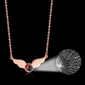 Detailed view of angel wing necklace showing 100 languages I love you projection stone