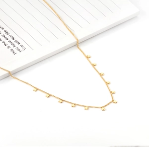 Detail of minimalist gold-tone stainless steel chain necklace with multiple star pendants