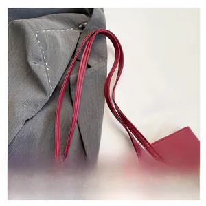 Détail du sac cabas bordeaux avec bandoulière, boucle en métal doré et texture cuir grainé