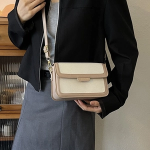 Sac à bandoulière carré chic bicolore avec garniture dorée dans un décor minimaliste