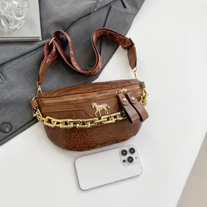 Detail van bruine tas met krokodillenprint, gouden ketting en logo van een klein paard