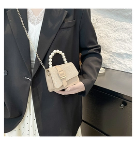 Détail du mini sac beige avec poignée en perles et tissu scintillant sur mannequin