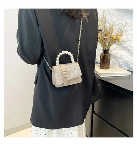 Détail du mini sac bandoulière en tweed beige avec poignée perle et chaîne dorée