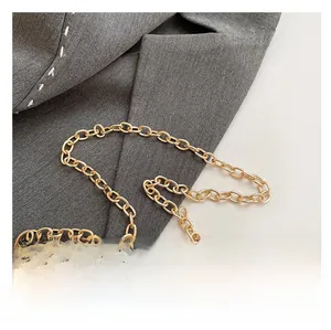 Détail d'une chaîne dorée brillante sur tissu gris, montrant la structure à maillons en O