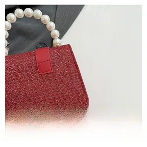 Détail du sac à main rouge à paillettes avec anse en perles blanches et fermoir cousu