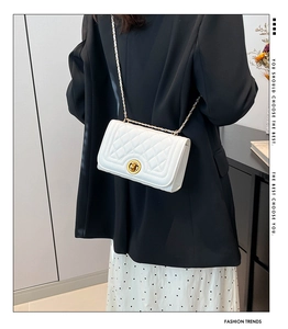 Detail of white quilted leather bag featuring gold chain strap and turn-lock closure