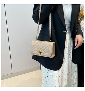 Detail of beige quilted shoulder bag with gold chain strap and metal swivel lock