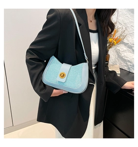 Detail of light blue underarm bag with sequin texture and golden circular twist lock