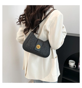 Detail of black sequined underarm bag with gold lock worn on a cream blazer
