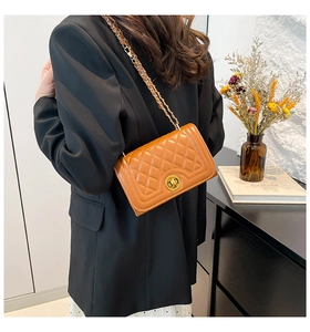 Detail of a brown quilted leather shoulder bag with gold hardware and chain strap