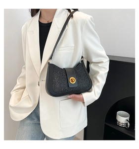 Model wearing black sequined shoulder bag with gold twist lock and matte leather strap