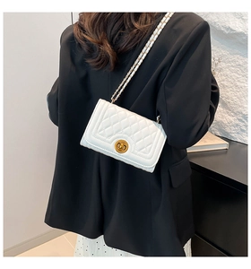Close-up of a white quilted crossbody bag with a gold chain strap and circular lock