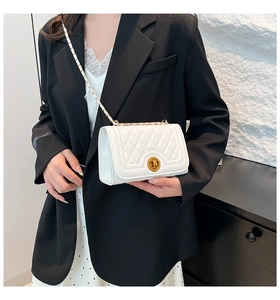 Detail of white quilted crossbody bag with golden chain strap and round turn-lock buckle