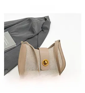 Detailed macro view of beige leather shoulder bag with woven texture and gold metal lock
