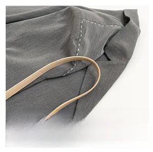 Detail of grey textured fabric bag with khaki leather strap and contrast stitching