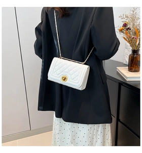 White quilted crossbody bag with gold chain strap shown on model's back in a modern room