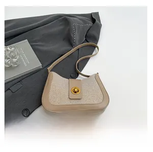 Detail of light brown and beige patchwork handbag with golden rotary buckle and clean stitching