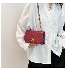 Close-up of wine red quilted crossbody bag with gold chain and metal twist lock