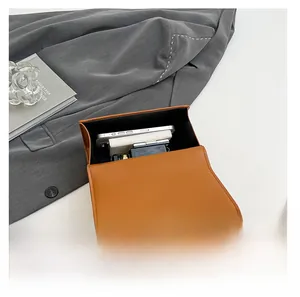 Detail showing the internal storage capacity for phone and cosmetics in the brown crossbody bag