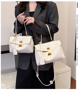 Detail of white lychee leather bags with golden twist locks in two sizes on model