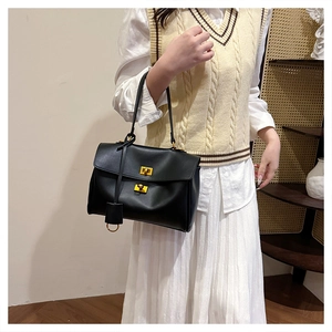 Close-up of black leather tote with gold metal twist locks shown on model