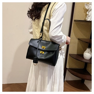 Detail of black leather tote bag featuring dual gold twist locks and leather hangtag detail