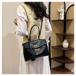 Close-up of black tote bag with golden twist lock and elegant round pendant detail