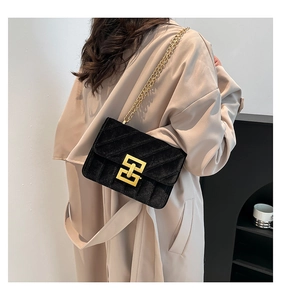 Détail du sac bandoulière en velours noir avec chaîne dorée et fermoir géométrique sur modèle