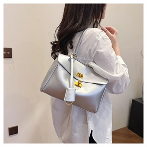 Close-up of silver leather tote bag with golden twist-lock buckles on a female model