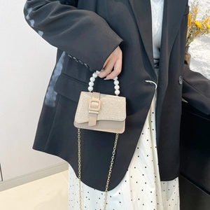 Sac à main beige élégant avec poignée en perles et rabat à paillettes sur mannequin