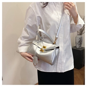 Detail showing the elegant golden metal twist lock and silver textured material of the bag