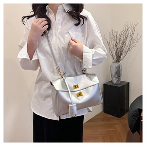 Silver metallic tote bag with golden lock shown on a model in a minimalist interior