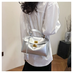 Detail of silver metallic tote bag with gold twist lock shown on model's shoulder