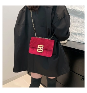 Détail du sac à bandoulière en velours bordeaux avec chaîne dorée sur un mannequin