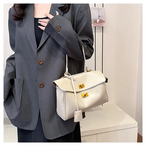 Detail of creamy beige leather tote bag with gold twist locks worn with a grey blazer