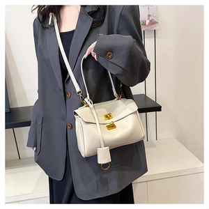 Detail of off-white tote bag featuring a gold twist lock and smooth leather texture