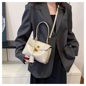 Detail of off-white leather tote featuring gold twist lock and elegant crossbody strap