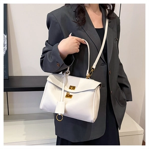 Detail of white leather tote bag with gold twist lock on a model in gray blazer
