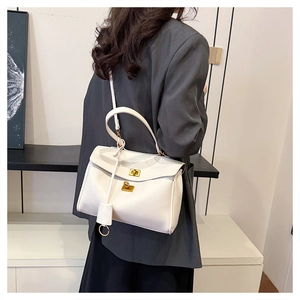 Side view of white leather crossbody bag with gold twist lock and adjustable shoulder strap